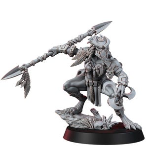 May include: A gray, detailed miniature figure of a warrior in a crouching pose, holding a spear with feather accents. The figure has a mask, armor, and a crescent-shaped blade. It stands on a base with skulls and a textured surface.