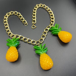 Vintage kitscherige plastic ketting met ananasfranje, dikke gele en groene ananas aan dikke goudkleurige ketting