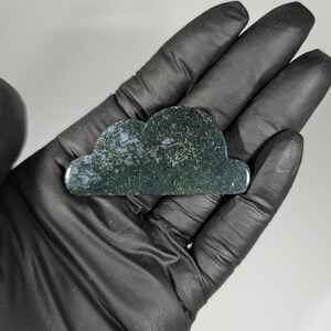 May include: A green and blue cloud-shaped gua sha tool made of natural stone. The tool is smooth and polished, with a slightly textured surface.