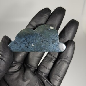 May include: A dark gray, cloud-shaped, polished stone with a smooth, slightly textured surface.