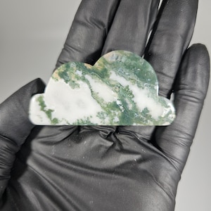 May include: A green and white agate cloud shaped stone. The stone has a swirling pattern of green and white.