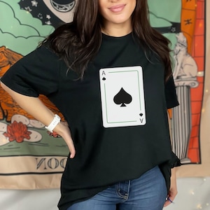 May include: Black t-shirt with a white graphic of the Ace of Spades playing card.