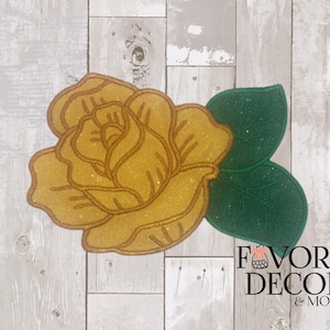 May include: A decorative, glittery yellow rose with a gold outline and two green leaves. The rose is set against a light wood-grain background. The text "FAVORS DECOR & MORE" is visible in the lower right corner.