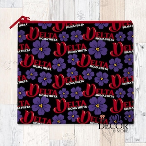 May include: A black zippered pouch with a repeating pattern of purple flowers and the words "DELTA SIGMA THETA" in red. The zipper and trim are red. The pouch is rectangular and likely made of fabric.
