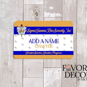 May include: A rectangular name tag with rounded corners, featuring a gold border and a blue stripe. The tag includes the text "Sigma Gamma Rho Sorority, Inc." and space to add a name and chapter. The bottom reads "Greater Service, Greater Progress."