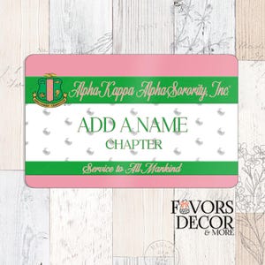 Op de afbeelding: Een rechthoekig roze en groen naambadge met de tekst "Alpha Kappa Alpha Sorority, Inc." en "ADD A NAME CHAPTER". De badge heeft een witte achtergrond met parelaccenten en de woorden "Service to All Mankind".