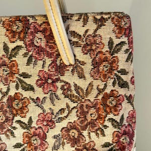 Peut inclure: Sac &agrave; main vintage avec un motif floral en tapisserie dans les tons de rouge, orange et vert sur fond cr&egrave;me. Le sac est de forme rectangulaire avec une poign&eacute;e cr&egrave;me.