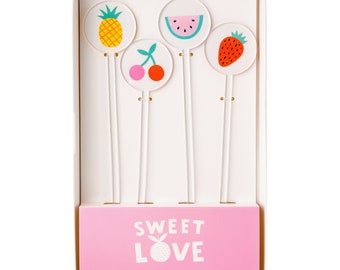 May include: A set of four acrylic drink stirrers with colorful fruit designs. The stirrers are packaged in a white box with a pink bottom that says "Sweet Love Acrylic Drink Stirrer Set" and a small logo that says "joyeux".