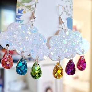 May include: A pair of earrings featuring a white glitter cloud with dangling raindrops in various colors, including red, blue, green, yellow, and purple.
