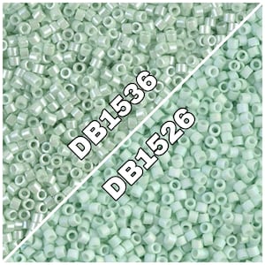 Peut inclure: Une image en gros plan d'une grande quantité de petites perles rondes de couleur vert clair. Les perles sont disposées de manière aléatoire. L'image est divisée en diagonale avec le texte "DB1536" sur la moitié supérieure et "DB1526" sur la moitié inférieure.