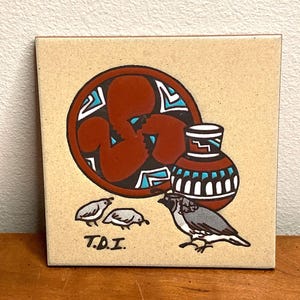 May include: A ceramic tile with a Southwestern design featuring a red and black pottery bowl, a brown and white pottery vase, and three small birds. The tile is signed "T.D.I."