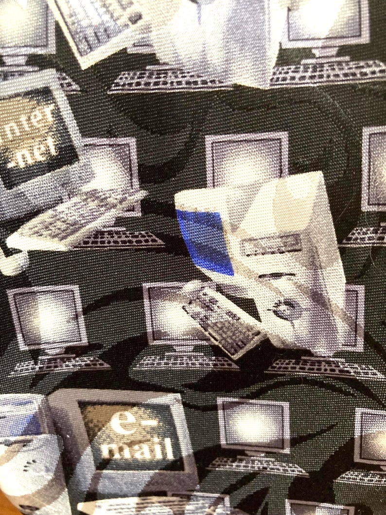 May include: A dark green necktie with a repeating pattern of computer monitors, keyboards, and the words "internet" and "e-mail" in white. The computer graphics are in shades of gray and white.