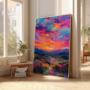 May include: A framed landscape painting with a vibrant sunset. The artwork features a colorful sky with shades of orange, pink, and purple. The foreground depicts a valley with a river and colorful vegetation. The frame is gold.