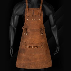 May include: A brown leather apron with multiple pockets and adjustable straps. The apron has a rugged, worn appearance, with visible stitching and metal rivets. It features a chest pocket and a large lower pocket with multiple compartments, ideal for a craftsman or artisan.