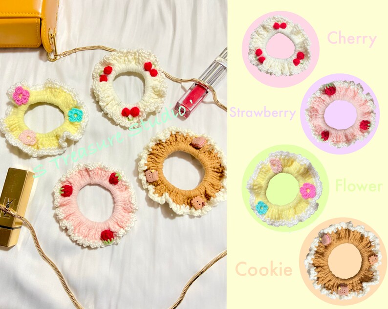 May include: Five crocheted hair scrunchies with different designs. The scrunchies are in the colors white, yellow, pink, brown, and beige. The designs include cherries, strawberries, flowers, and cookies. The scrunchies are labeled "Cherry", "Strawberry", "Flower", "Cookie", and "Flower".