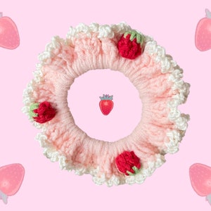 May include: A pink crocheted hair scrunchie with white lace trim and strawberry embellishments.