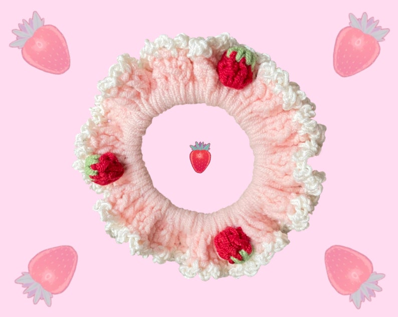 May include: A pink crocheted hair scrunchie with white lace trim and strawberry embellishments.
