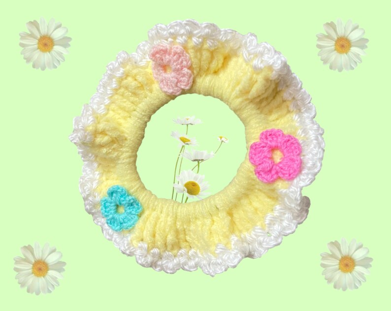 May include: A yellow crocheted hair scrunchie with white trim and three crocheted flowers in pink, blue, and light pink.