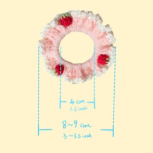 May include: A pink crocheted hair scrunchie with white lace trim and red strawberry embellishments. The scrunchie measures 4 cm (1.6 inches) in diameter and 8-9 cm (3-3.5 inches) in circumference.
