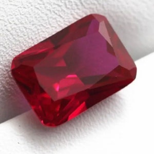 May include: A deep red gemstone with a rectangular cut and a high polish.