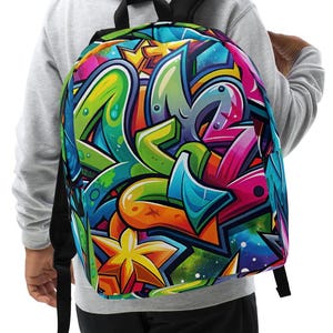 Könnte beinhalten: Ein bunter Rucksack mit einem Graffiti-Design mit leuchtenden Farben, Sternen und abstrakten Formen.