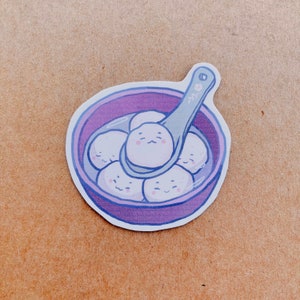 May include: A sticker featuring a purple bowl filled with white, smiling dumplings. A spoon scoops up some of the dumplings. The spoon and bowl have a light purple outline. The sticker has a white border.