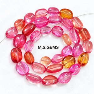 Pode incluir: Um fio de contas de pedras preciosas translúcidas de formato oval em tons de rosa, magenta e laranja. As contas estão enfiadas num fio fino e o texto M.S.GEMS está impresso a preto no centro da disposição circular.