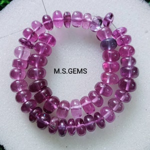 May include: Strands of polished, translucent, oval-shaped beads in varying shades of pink and purple. The beads are strung together, forming a necklace or bracelet. The text "M.S. GEMS" is visible in white.