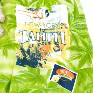 May include: A light green fabric with a tropical print featuring palm trees and a vintage travel graphic. The graphic reads "New York to Tahiti" with images of an airplane and a woman. A "Hotel Bahama" patch is also visible.