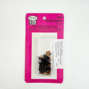 May include: A package of HO scale model train couplers. The package is pink and white, with the text "#10 SUPER PACK 10 pair" and "All metal #5 Couplers". The couplers are black and gold-colored metal.