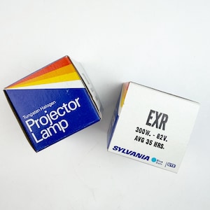 May include: Two boxes of projector lamps. One box is blue with the text "Projector Lamp" and a colorful stripe design. The other box is white with the text "EXR" and "300W. - 82V. AVG 35 HRS."