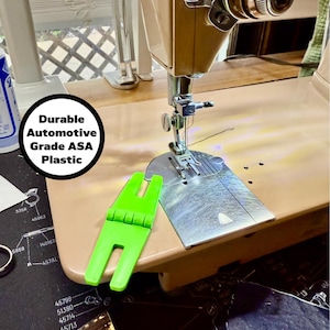 May include: A vintage beige sewing machine with a bright green plastic attachment. The machine has a silver needle plate and a circular dial. The text "Durable Automotive Grade ASA Plastic" is in a white circle.
