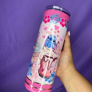 May include: A pink glitter tumbler featuring a cartoon character design. The tumbler has a pink glitter top and bottom, with a white center decorated with hearts, flowers, and the cartoon character. The design includes a pink milkshake and the cartoon character.