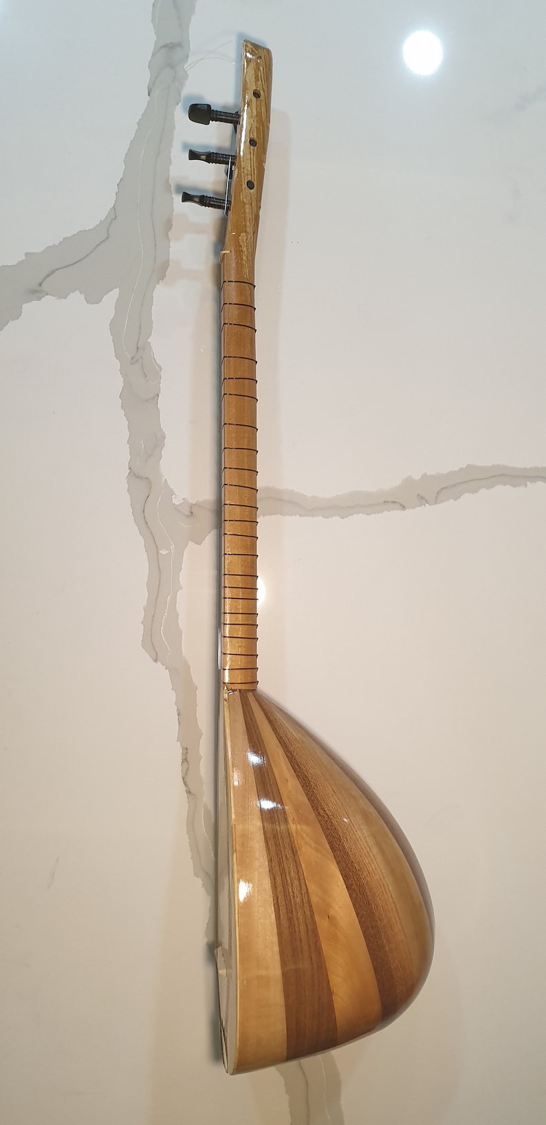 May include: A wooden stringed instrument with a pear-shaped body and a long neck. The instrument is made of light and dark wood and has a glossy finish.