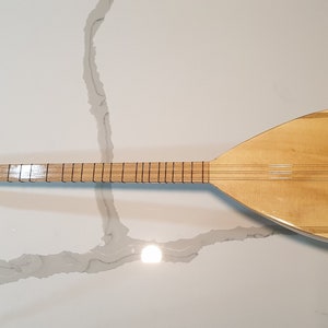 May include: A wooden  saz, a Turkish stringed instrument, with a pear-shaped body and a long neck. The saz has a natural wood finish and black tuning pegs.
