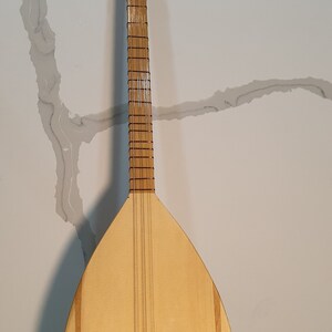 May include: A wooden long-necked lute with a pear-shaped body, a natural wood finish, and black tuning pegs. The body has two thin black stripes running down the sides.