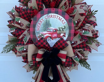 May include: A red and black buffalo plaid Christmas wreath with a red truck and "Merry Christmas" sign. The wreath is decorated with burlap ribbon, evergreen sprigs, and a black velvet bow.