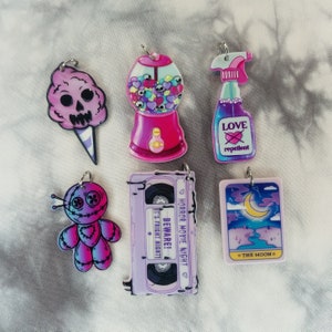 May include: A set of six colorful charms featuring a skull-shaped cotton candy, a gumball machine, a spray bottle with the text "Love repellent", a voodoo doll, a cassette tape with the text "Horror Movie Night Beware! It's Fright Night", and a tarot card with the text "The Moon".