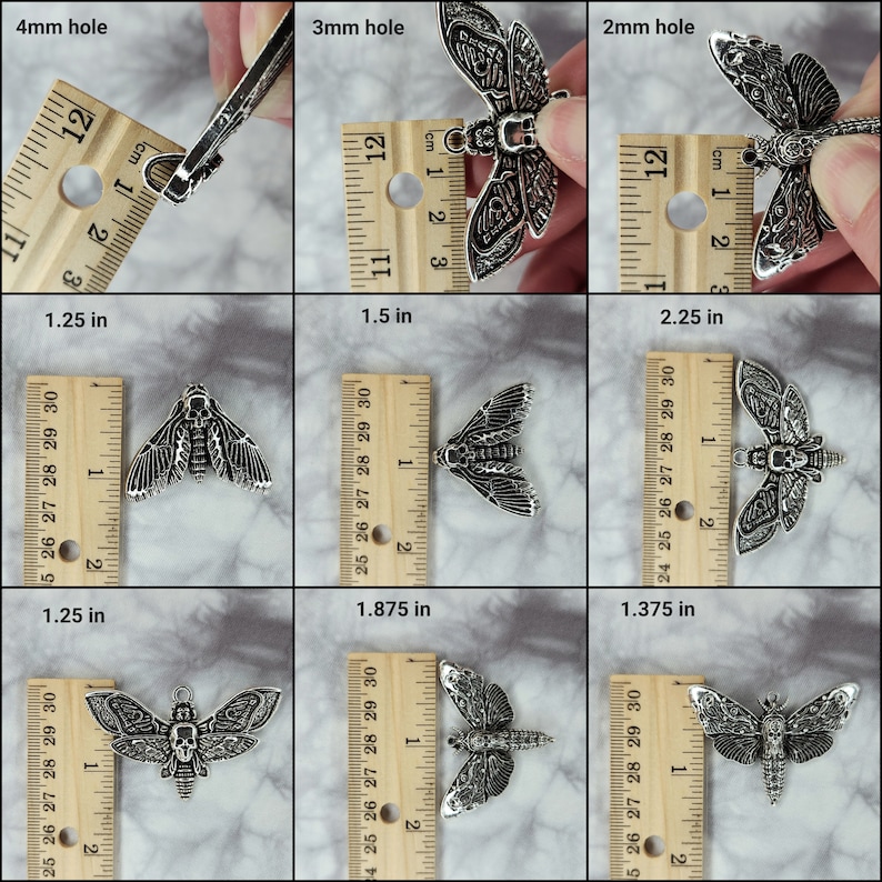 Puede incluir: Tres abalorios de metal de color plateado en forma de polilla con detalles de calavera. Los abalorios se muestran junto a una regla para mostrar su tama&ntilde;o. Los abalorios miden 3,18 cm, 4,76 cm y 3,49 cm de largo.