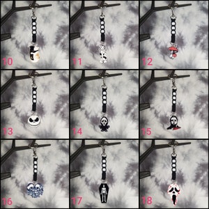 May include: A set of 9 Halloween-themed keychains featuring various characters and designs. The keychains are black and white with a black cord and a silver key ring. The characters include a cat, a ghost, a mushroom, Jack Skellington, a ghost with a knife, Michael Myers, a skull, a skeleton, and Ghostface.
