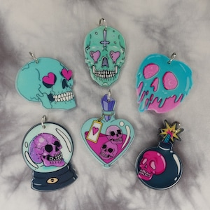 May include: Set of six colorful skull charms with different designs. The charms are made of acrylic and feature a variety of colors, including pink, blue, and green. The charms are perfect for adding a touch of whimsy to any jewelry project.