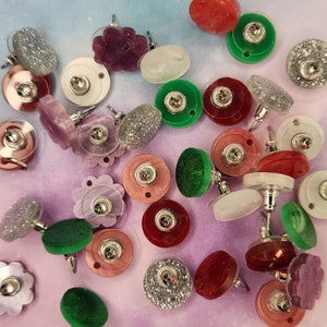 May include: Assortment of colorful and patterned earrings, including floral, geometric, and abstract designs. The earrings are made of various materials, such as metal, plastic, and glass.