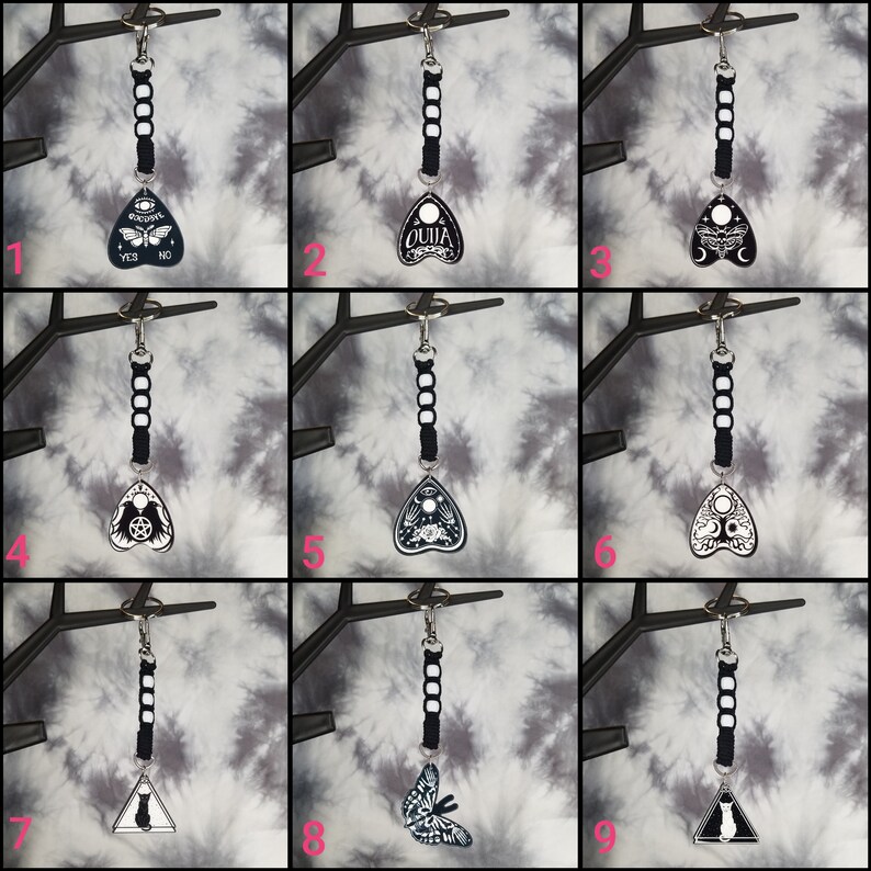 May include: Nine different black and white keychains with a triangular shape and various designs. The designs include a butterfly, a cat, a crescent moon, a pentagram, and the word "Ouija".