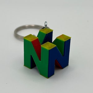 Może przedstawiać: Zielono-niebieski brelok do kluczy wydrukowany w 3D w kształcie logo Nintendo.