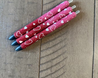 Bolígrafo epoxi con forma de corazón personalizado sobre fondo ombré rojo y rosa