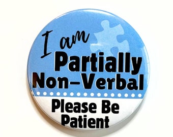 May include: A circular badge with a light blue background and the text "I am Partially Non-Verbal Please Be Patient". A puzzle piece graphic is visible on the top. The bottom half is white.
