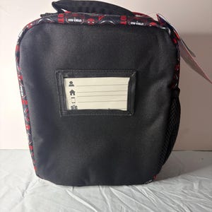 May include: Black lunch bag featuring a red and black Spider-Man pattern around the top and handle. It has a small clear window for a name tag. A black mesh pocket is on the side.