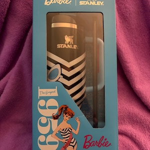 Puede incluir: Un juego en caja que presenta un termo Stanley en blanco y negro y una taza a juego, ambos con el logotipo de Stanley. La caja es azul claro y presenta el logotipo de Barbie y una ilustraci&oacute;n vintage de Barbie. Tambi&eacute;n se ve el texto "1959" y "The Original".