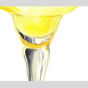 May include: A close-up of a yellow glass goblet with a silver stem. The goblet is filled with a yellow liquid.