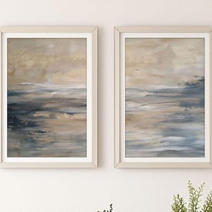 Puede incluir: Dos pinturas abstractas enmarcadas en una paleta de colores apagados de beige, marrón y azul. Las pinturas representan un paisaje marítimo con pinceladas que crean una sensación de movimiento y profundidad.